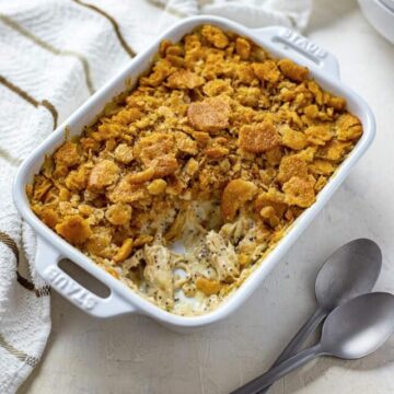 baked casserole in a white oblong dish with one serving removed and spoons on the side