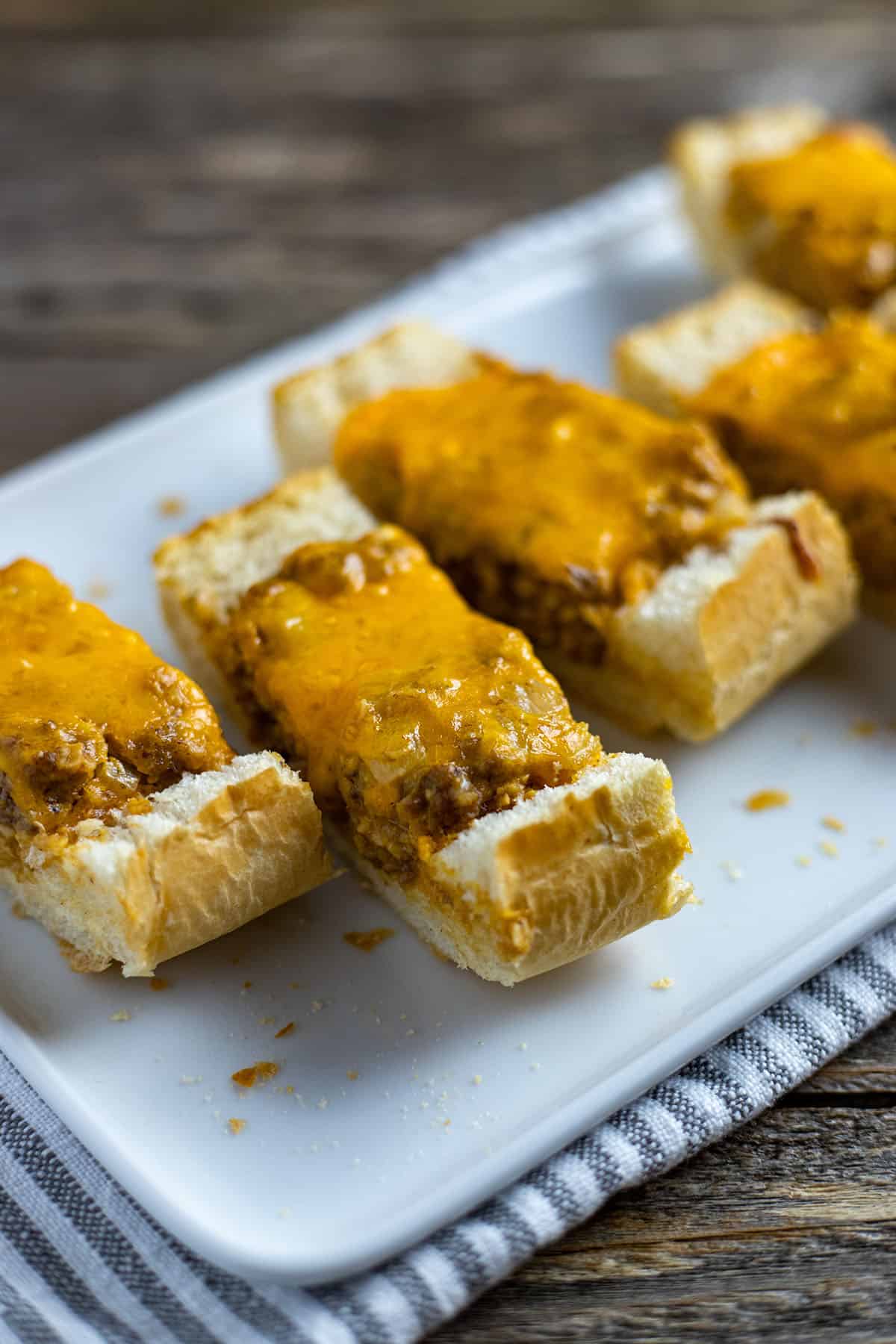 slices of baked stuffed french bread on a rectangular white plate on top of w blue striped white napkin