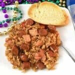 chicken and sausage jambalaya on white plate with mardi gras beads on the side