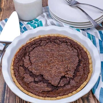 whole chess pie with glass of milk and white plates in background