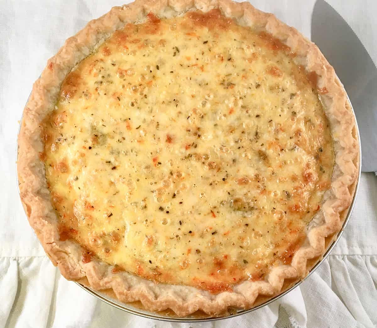 Overhead view of whole zucchini pie on a white napkin.