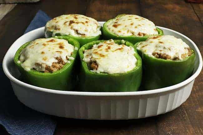 five cheesy baked stuffed bell peppers in white casserole dish