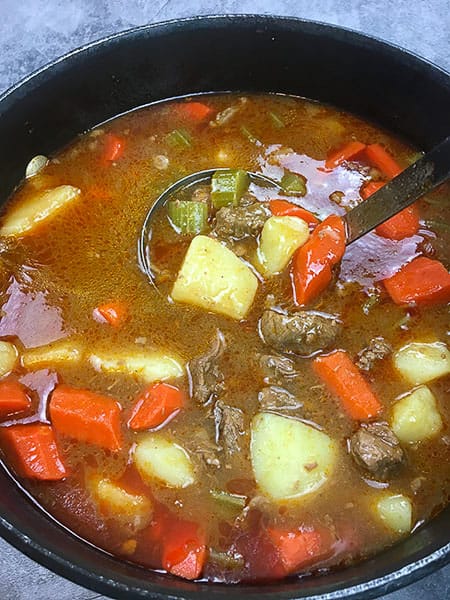 cooked beef stew in pot with ladle
