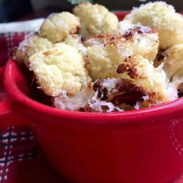 roasted cauliflower florets in red bowl topped with parmesan cheese