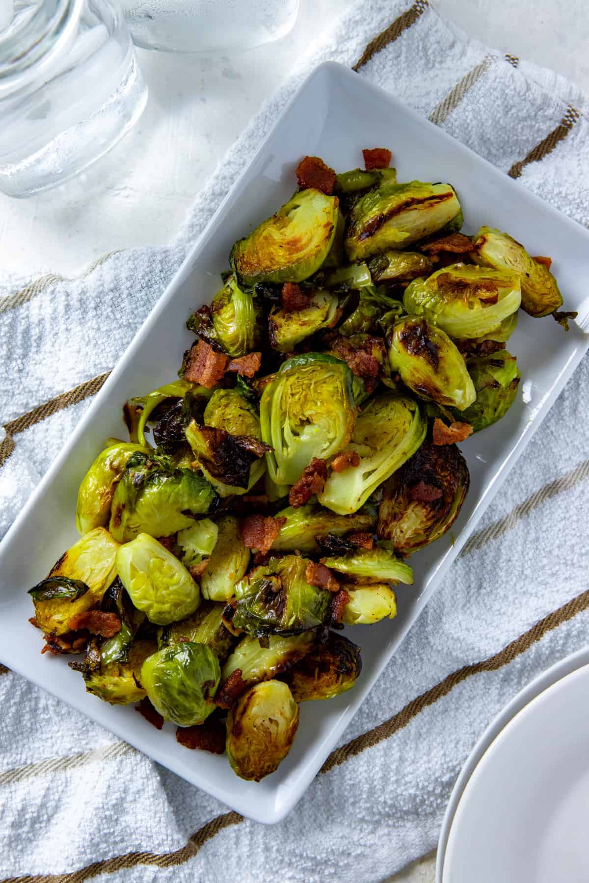 cooked brussels sprouts and bacon in white rectangular dish