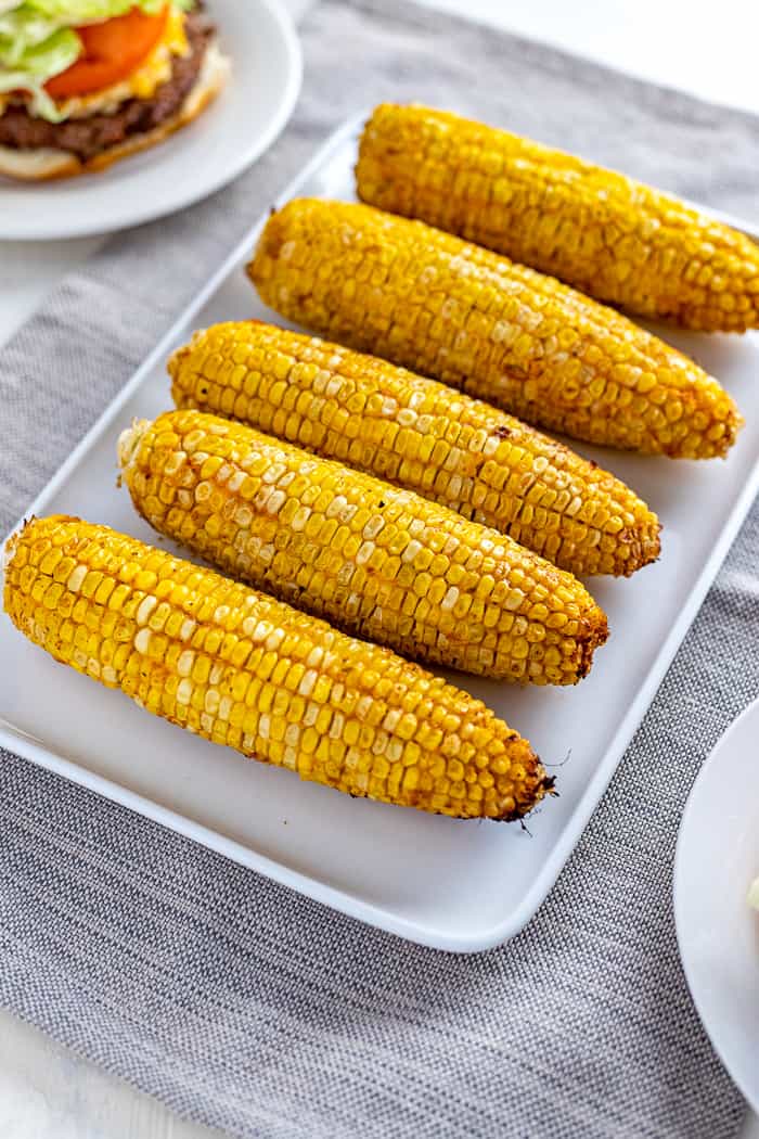 five ears of grilled corn on white rectangle platter