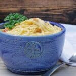 rotel chicken spaghetti in blue bowl with white napkin and fork