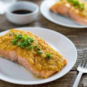 miso salmon fillet on white plate with green onion slices on top