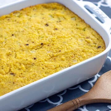 baked cornbread dressing in white rectangular casserole dish with wooden serving spatula on the side