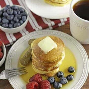 low carb pancakes on white plate with berries on side and syrup on top