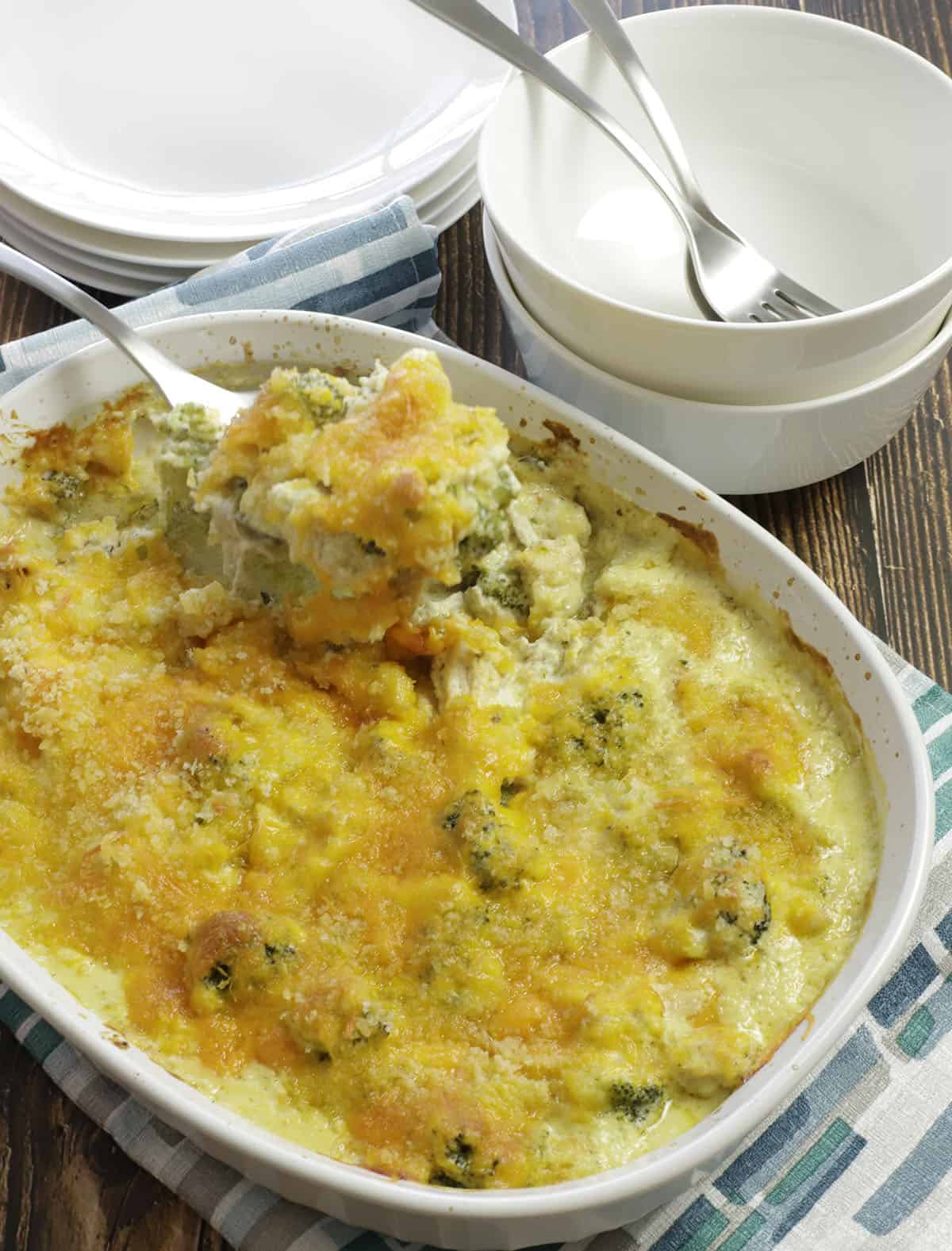 Baked casserole in oval white dish with silver spoon scooping out. 