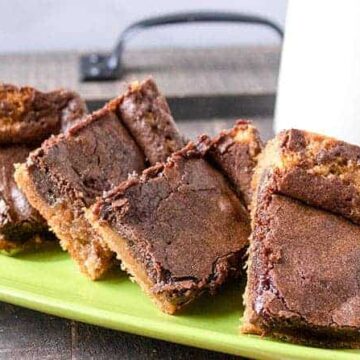 baked brownies on green plate with glass of milk