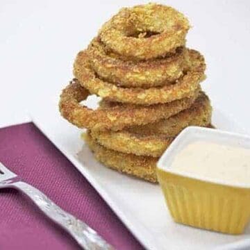 baked onion rings on white plate with dipping sauce