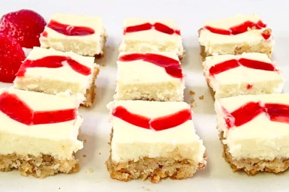 individual baked cheesecake squares with fresh strawberries in background