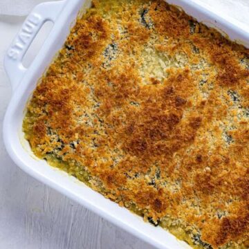 spinach mixture in white casserole dish topped with panko breadcrumbs