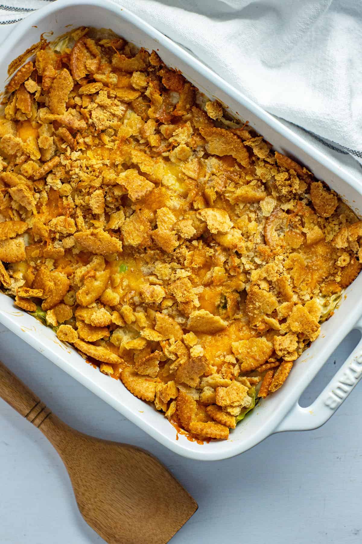 baked casserole in a white oblong dish with wooden serving spoon on the side