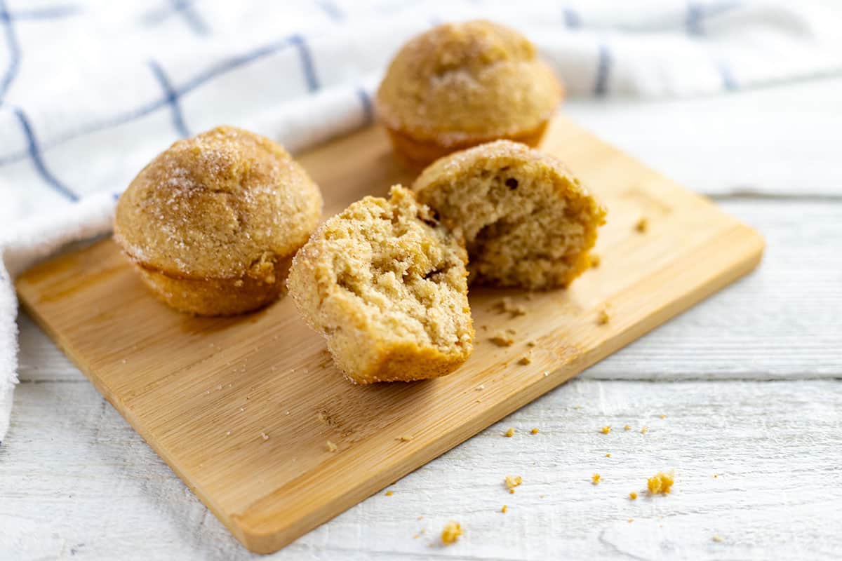 Baked cinnamon applesauce muffins on wooden cutting board.