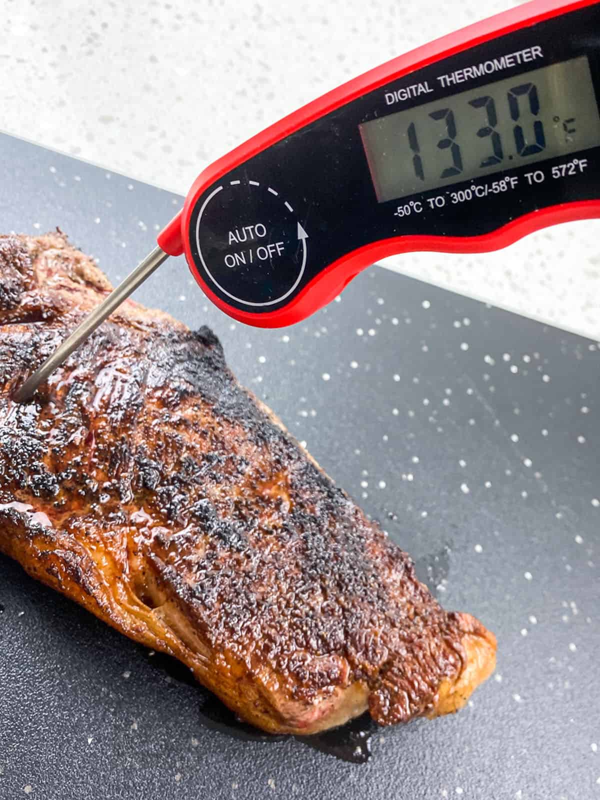 meat thermometer in cooked steak measuring 133F