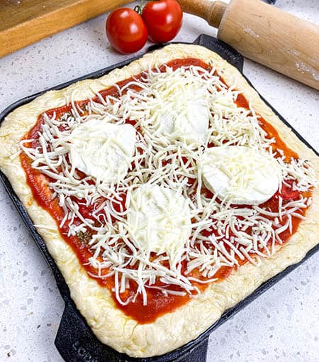 add mozzarella slices and shredded mozzarella to pizza