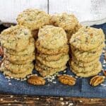 stacked baked cookies on blue napkin with pecan halves next to them