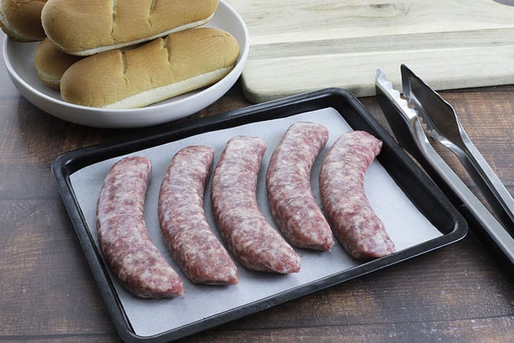 uncooked bratwurst sausages on sheet pan lined with parchment paper