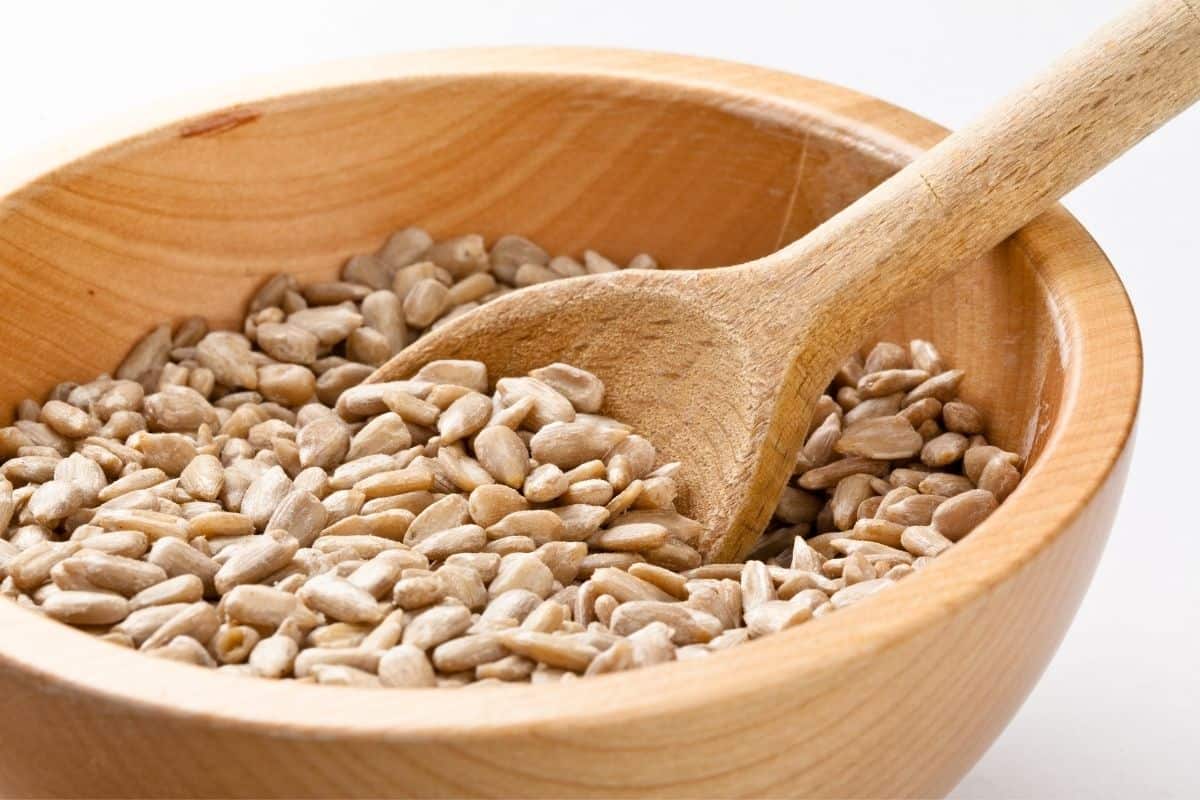 shelled sunflower seeds in wooden bowl with wooden spoon