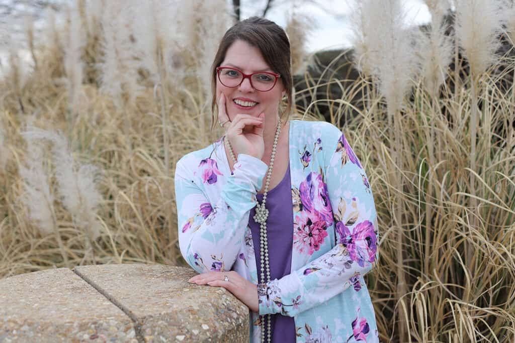 Profile picture pose outside in front of tall brown grass in lavender floral blouse