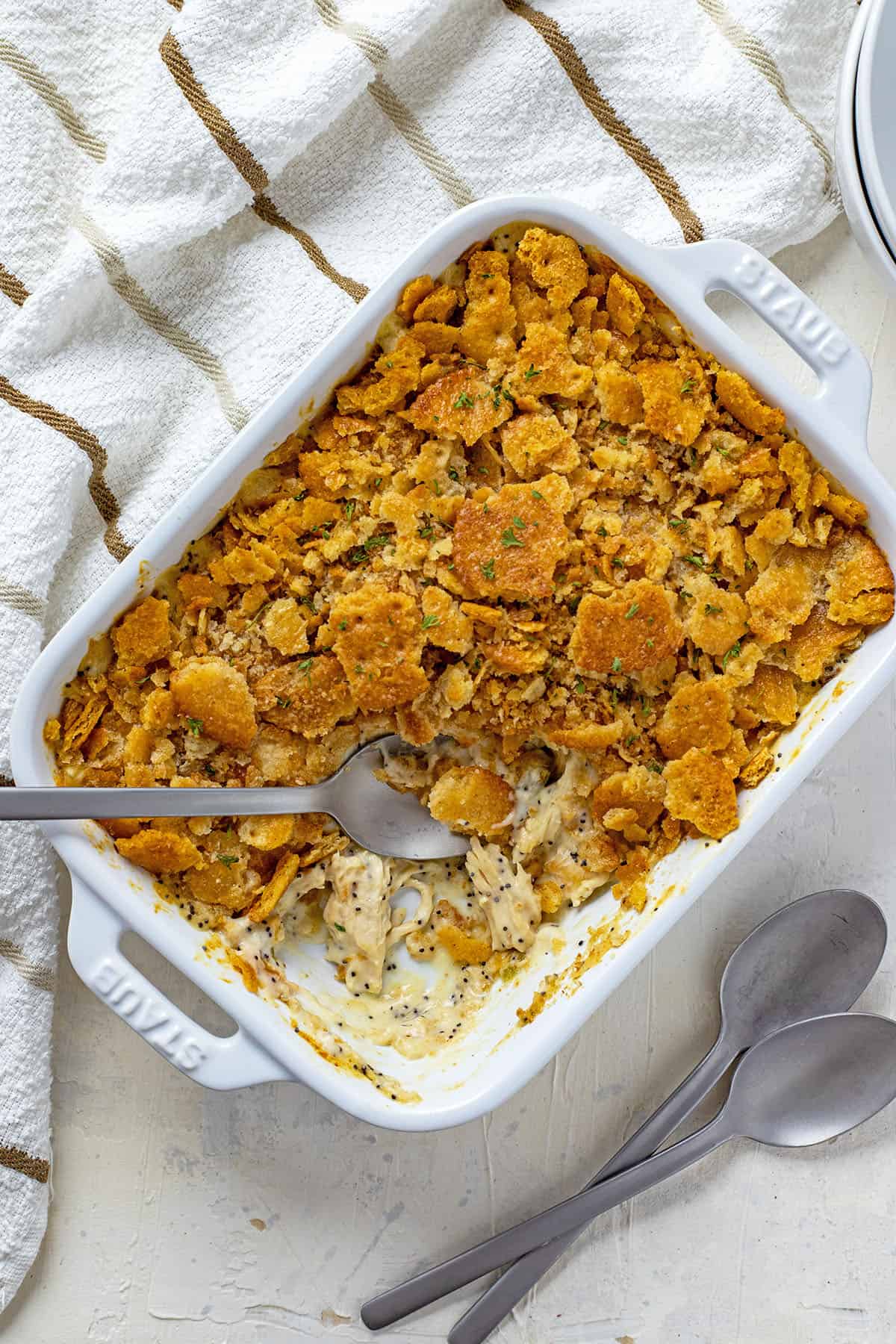 baked casserole in a white oblong dish with one serving removed and spoons on the side