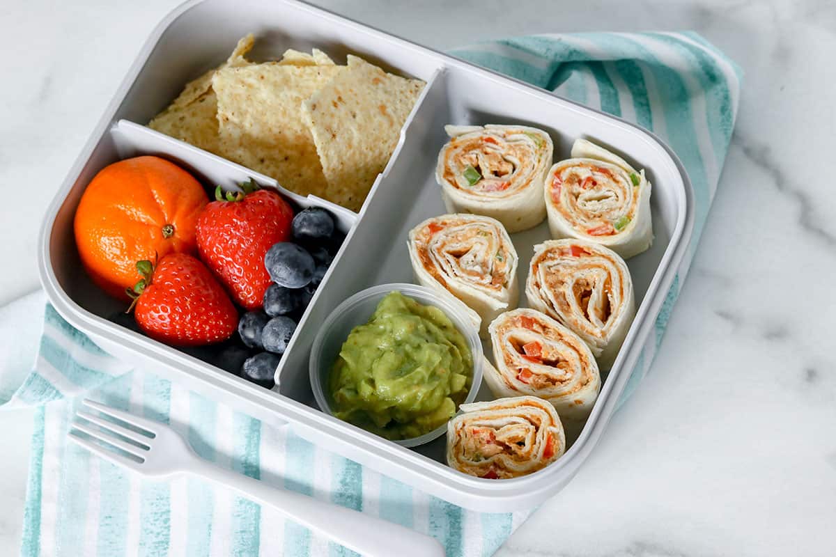 3 compartment lunch box with taco pinwheels, guacamole cup, corn chips, and fresh fruit
