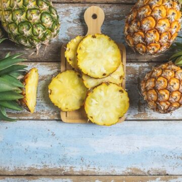 fresh pineapple cut up slices on wooden cutting board