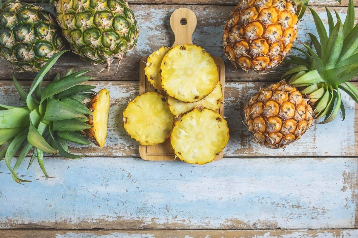 fresh pineapple cut up slices on wooden cutting board