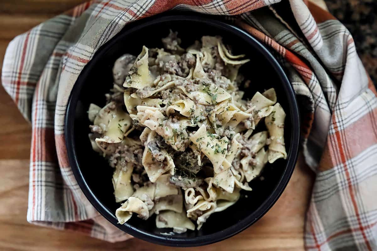 cooked stroganoff in black bowl with red plaid napkin