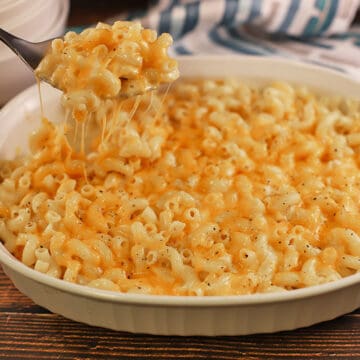 baked cheese macaroni in white oblong casserole dish with silver spoon scooping