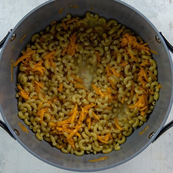 Cooked macaroni in a pot with butter, milk, cheese and seasonings.