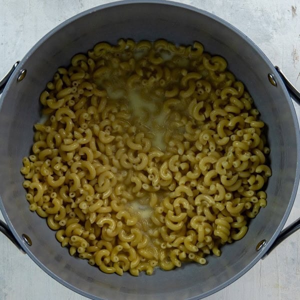 Cooked macaroni in a pot with butter and milk.