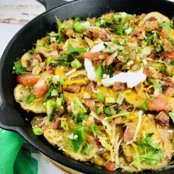 baked nachos in cast-iron skillet with green napkin on the side