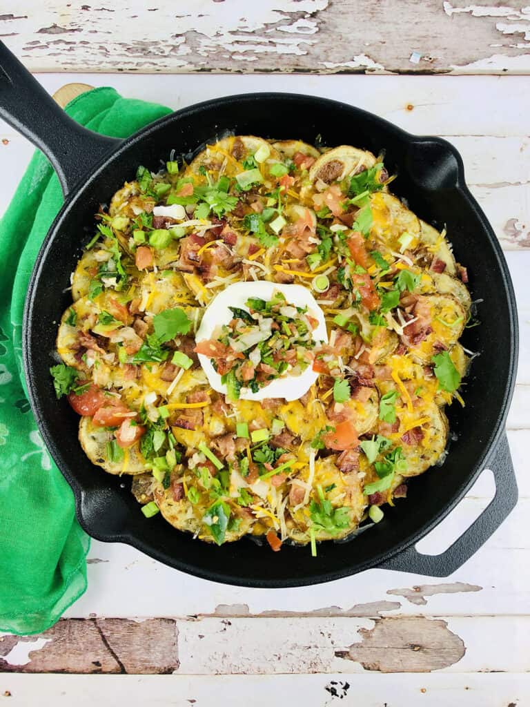 baked nachos in cast-iron skillet with green napkin on the side