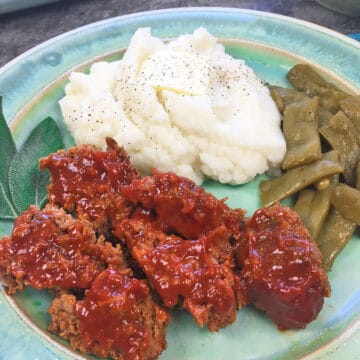 teal blue plate with a serving of meatloaf, mashed potatoes, and green beans