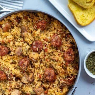 Cooked Chicken and Sausage Jambalaya in pan with toasted French bread on the side.