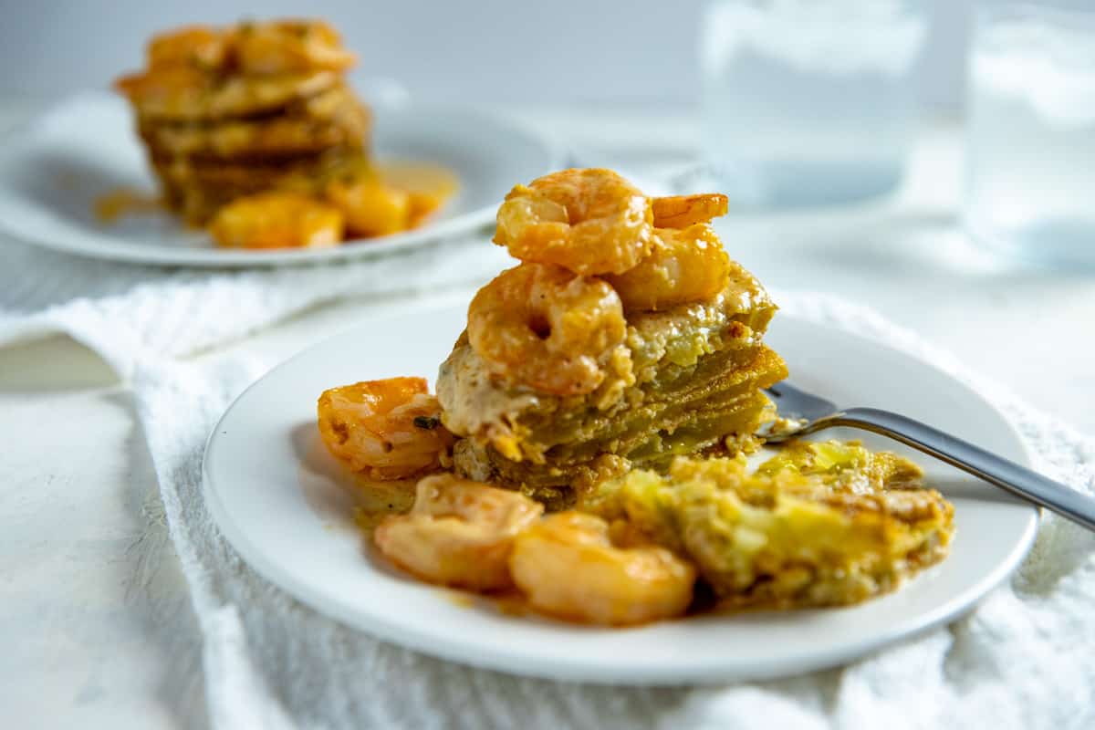 fried green tomatoes stacked on white plate with shrimp creole sauce poured on top