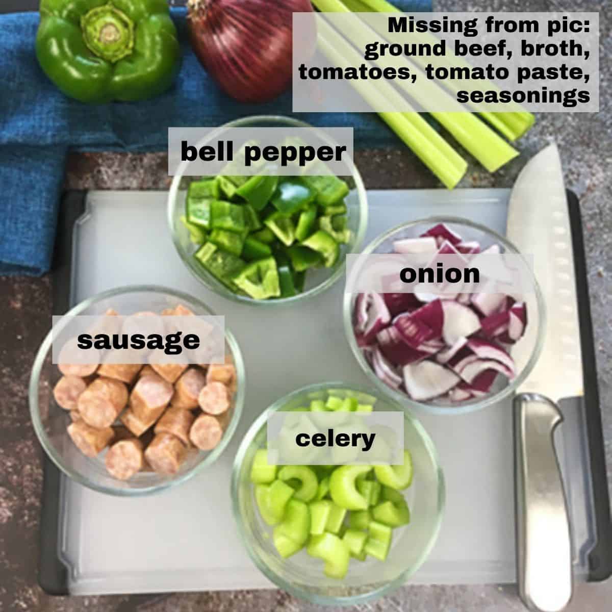Chili ingredients measured out in individual bowls on cutting tray with knife on the side.