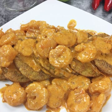 fried green tomatoes fanned across a white, square plate topped with shrimp sauce