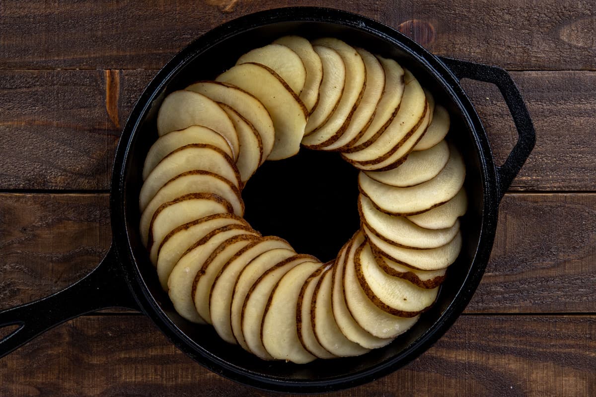 sliced potatoes layered in a cast iron skillet