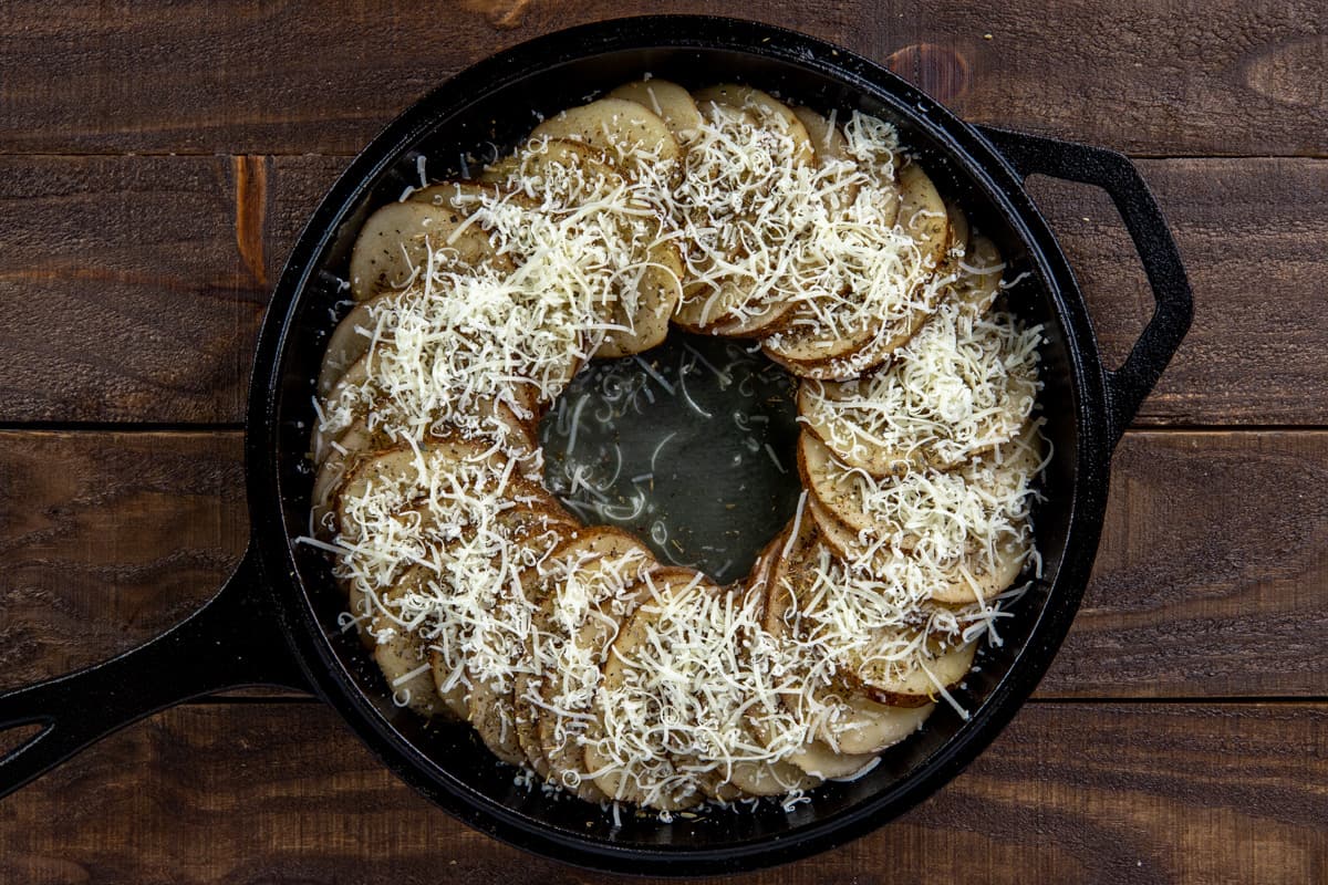 sliced potatoes in skillet with cheese on top