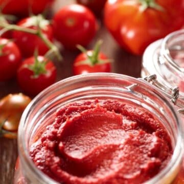 picture of tomato paste in mason jar with tomatoes in background