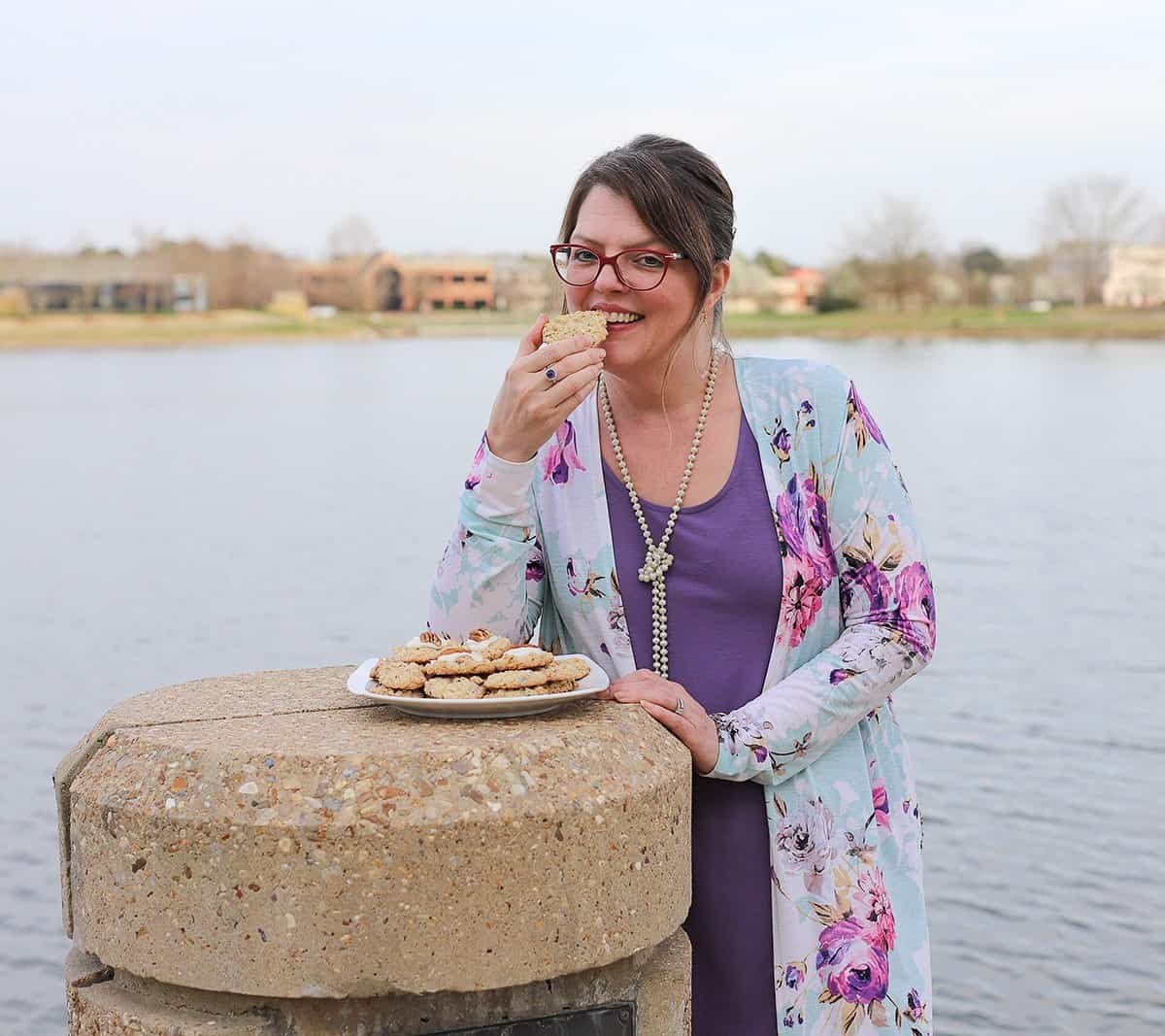 Anne Clark eating a cookie by the lake.