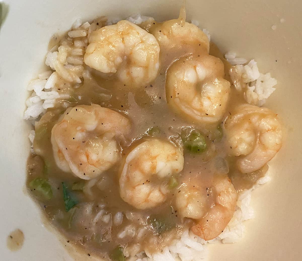 Shrimp stew on top of rice in a white bowl.