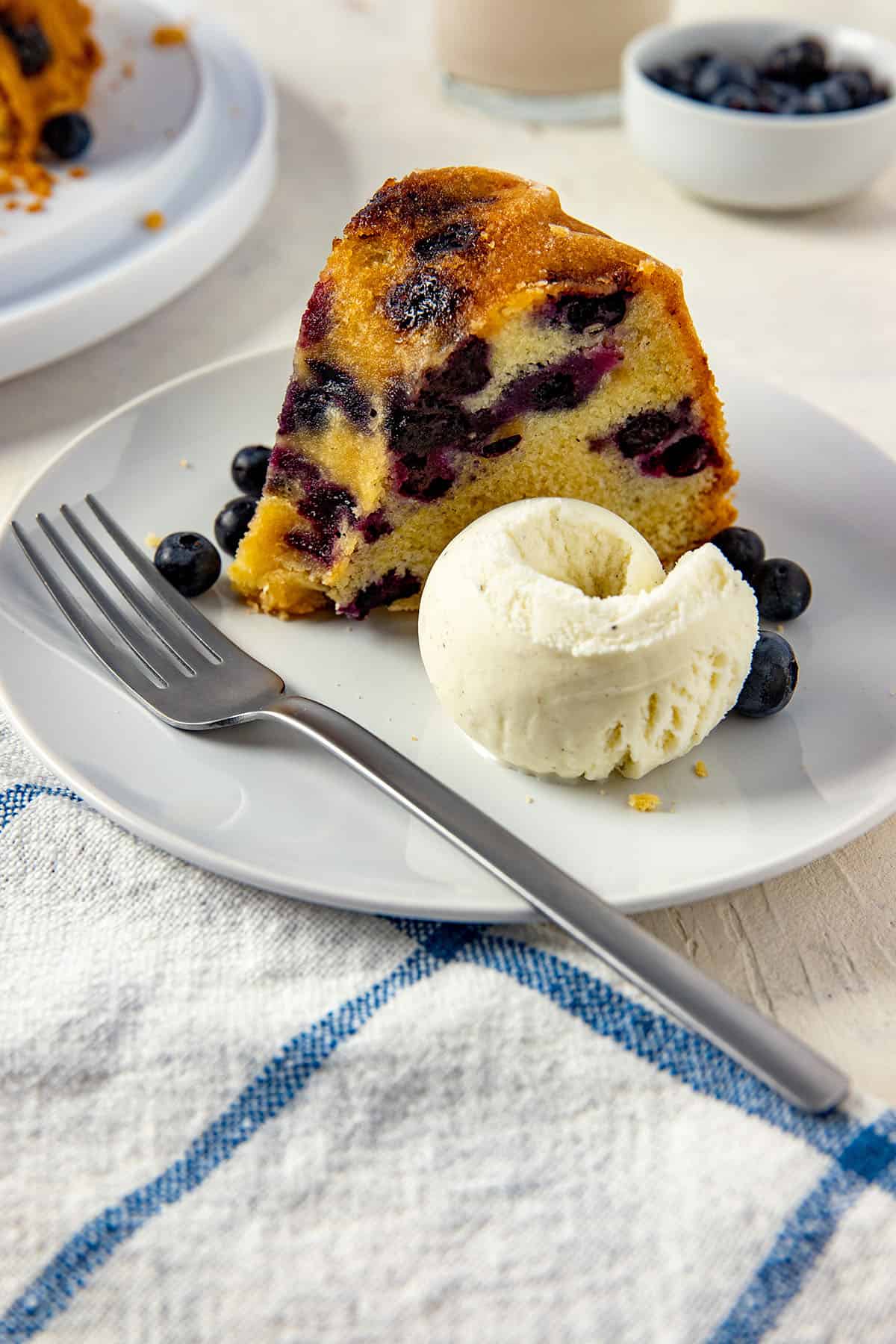 slice of cake on white plate with scoop of vanilla ice cream on the side.