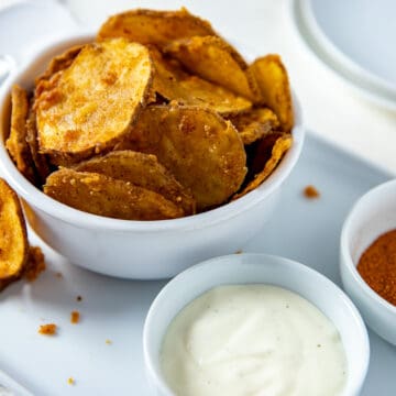 White bowl filled with fried potato slices plus a small bowl of ranch dressing on the side.