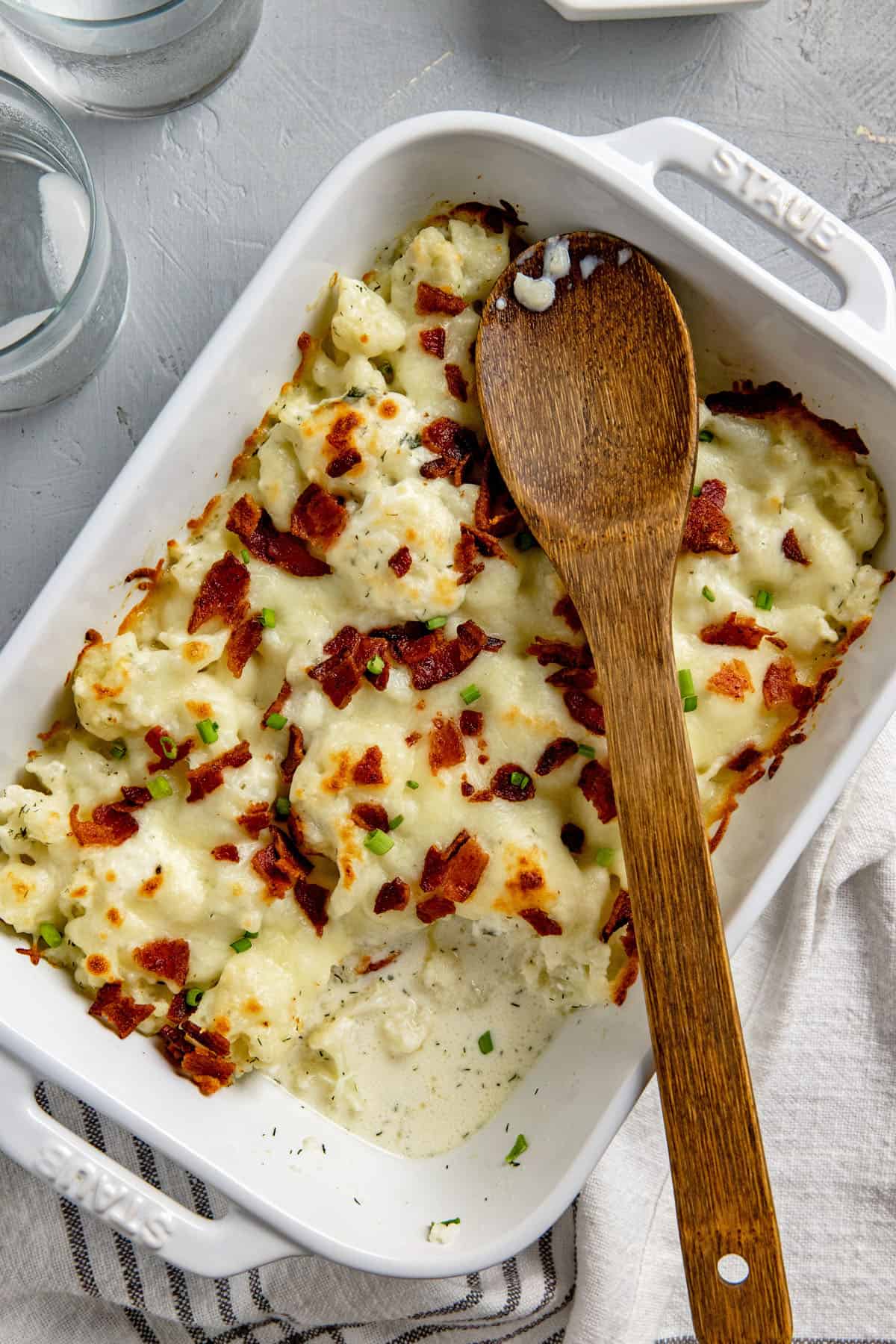 baked casserole in a white dish with wooden spoon on top